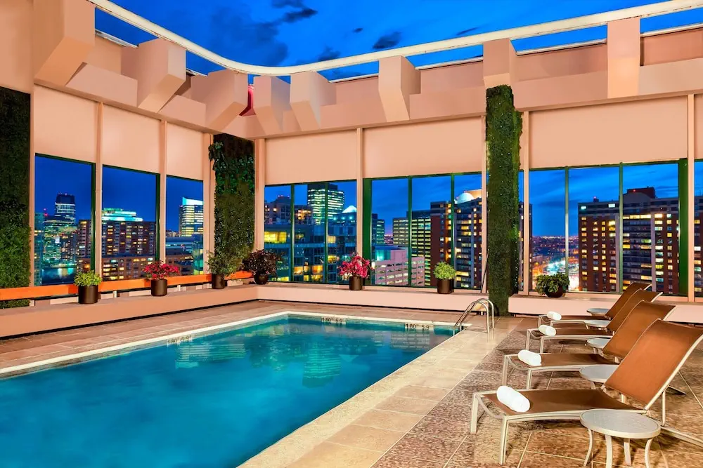 Outdoor pool at Sheraton Mexico City Maria Isabel Hotel, featuring a spacious, inviting swimming area surrounded by lounging chairs and lush greenery, epitomizing a luxurious urban oasis.